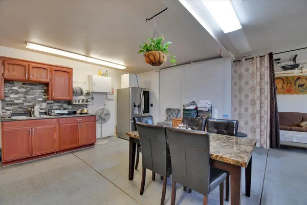 a kitchen with stainless steel appliances granite countertop a dining table chairs and white cabinets