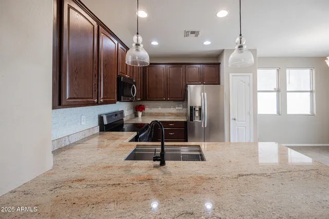 a kitchen with stainless steel appliances granite countertop a sink refrigerator and cabinets