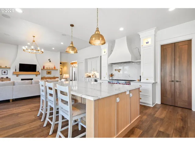 a kitchen with kitchen island granite countertop a stove a oven a dining table and chairs with wooden floor