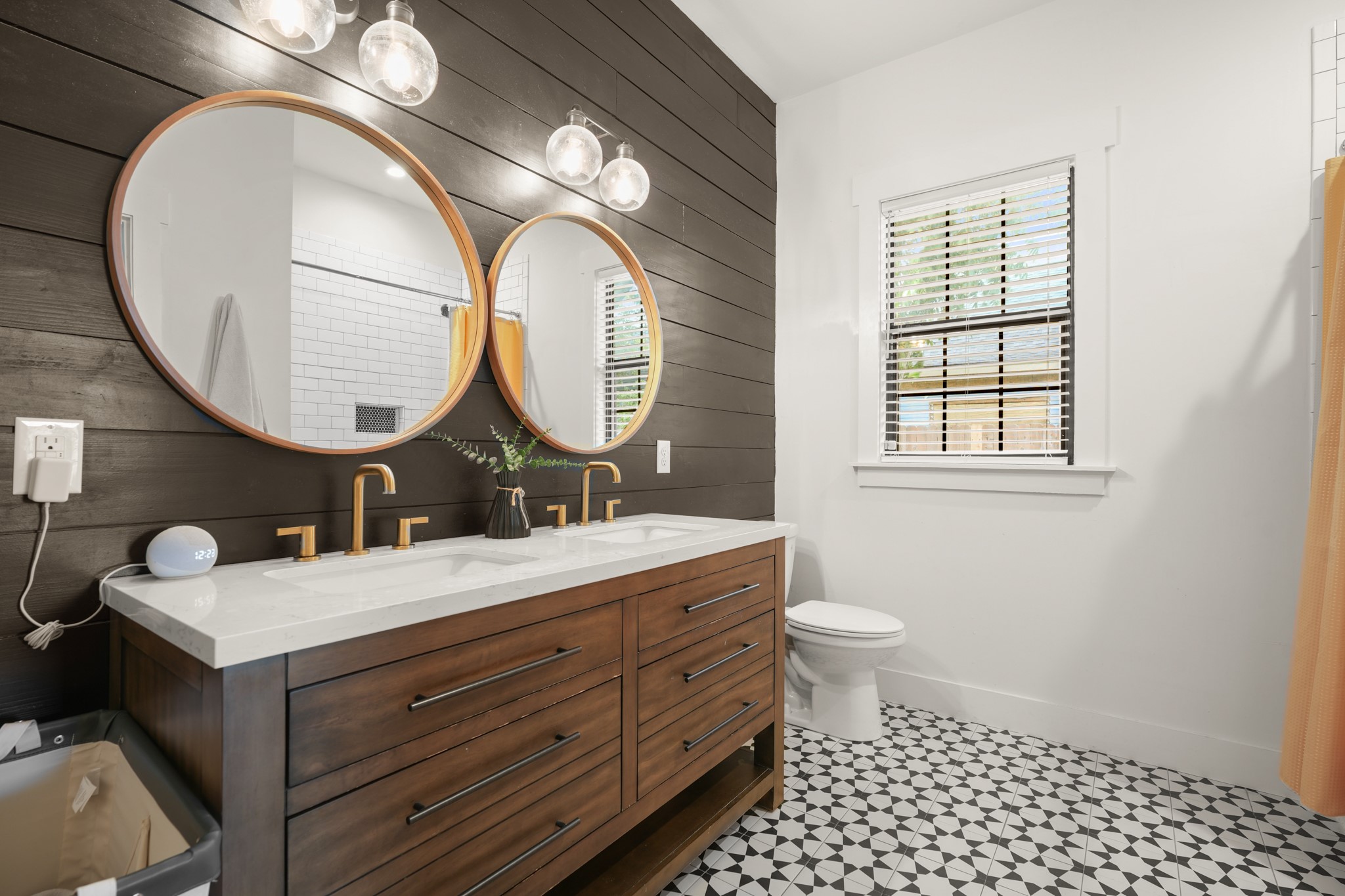 301 Old Thorndale Road Taylor, TX 76574 - Photo 9 of 29 A chic bathroom featuring a double vanity with striking gold fixtures, dark wood paneling, and a unique patterned tile floor.