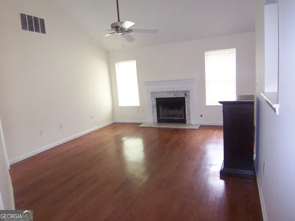 an empty room with wooden floor fireplace and windows