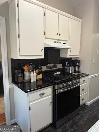 a kitchen with stainless steel appliances a stove and white cabinets
