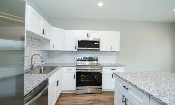 a kitchen with stainless steel appliances granite countertop a stove a sink and a refrigerator