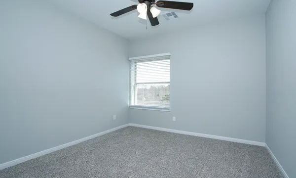 an empty room with a window and a fan