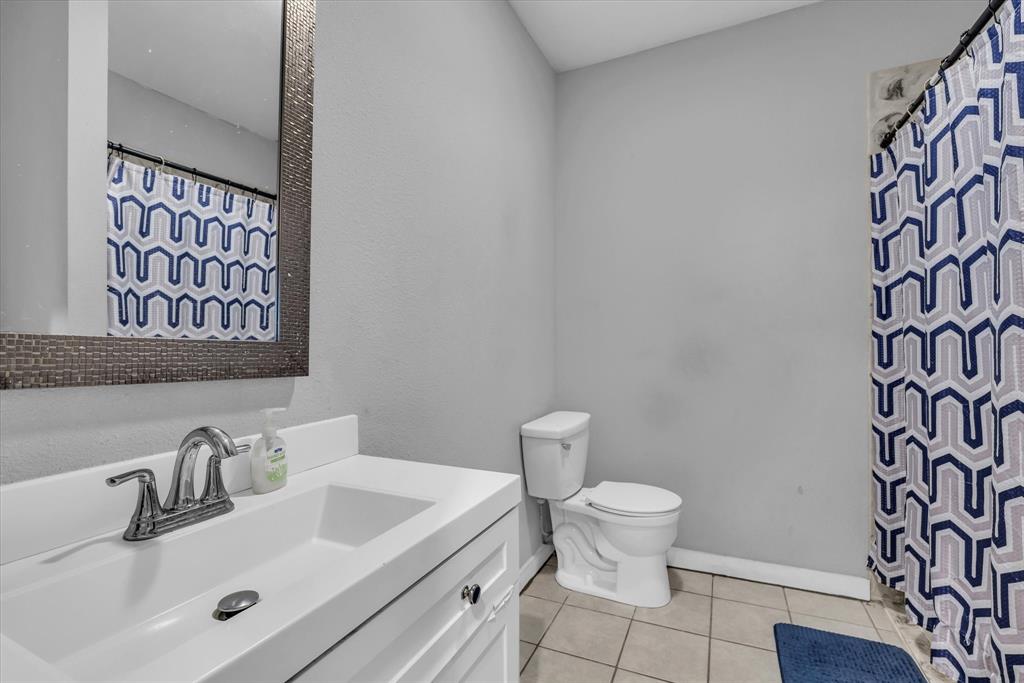 1822 Herring Avenue Waco, TX 76708 - Photo 9 of 26 a bathroom with a sink a toilet and shower curtain