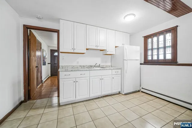 a kitchen with white cabinets and refrigerator