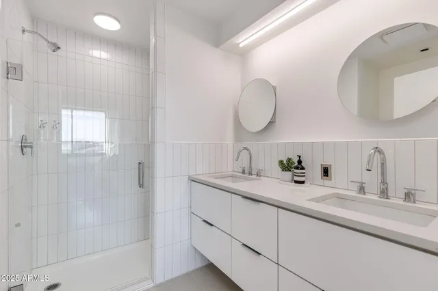 a bathroom with a double vanity sink mirror and shower