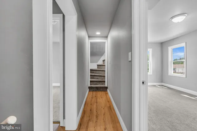 a view of a hallway with wooden floor and a bathroom