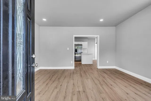 a view of a hallway with wooden floor and a kitchen