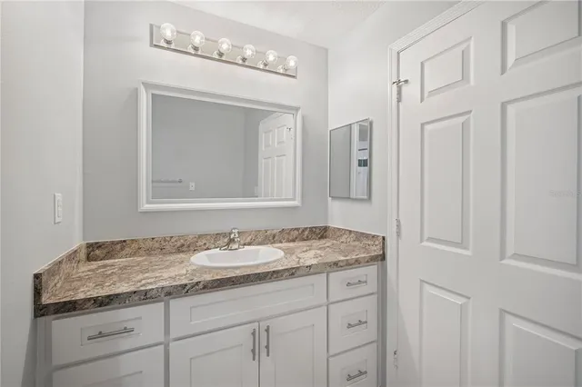 a bathroom with a granite countertop sink and a mirror