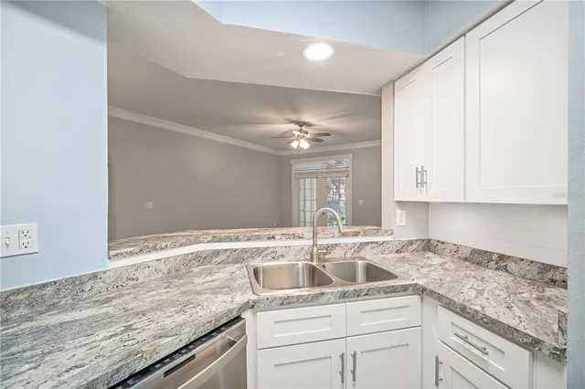 a kitchen with granite countertop a sink and white cabinets