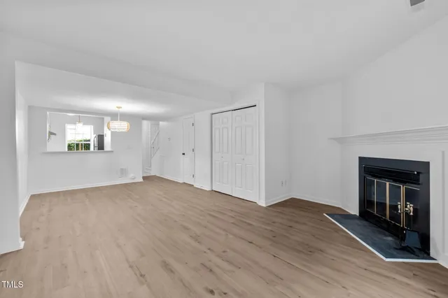 a view of an empty room with wooden floor and a fireplace