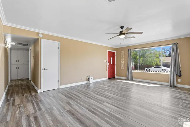 a view of empty room with wooden floor and fan