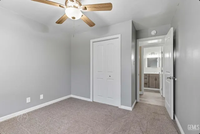 a view of an empty room and chandelier fan