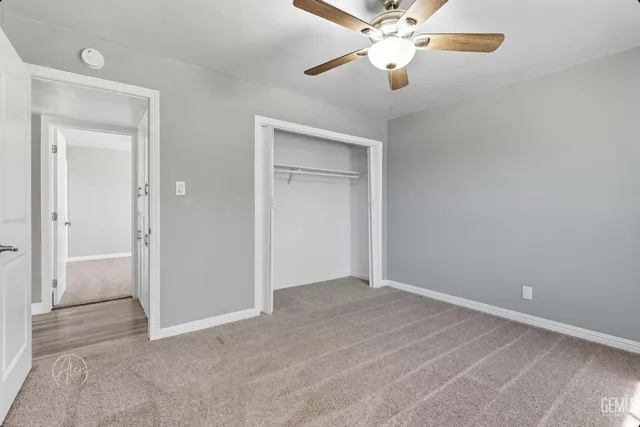 an empty room with closet and a chandelier fan