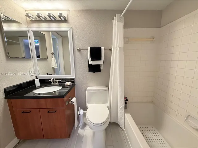 a bathroom with a granite countertop sink toilet a mirror and shower