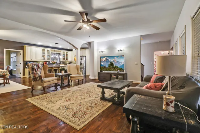 a kitchen with stainless steel appliances kitchen island granite countertop a refrigerator a stove and white cabinets with wooden floors