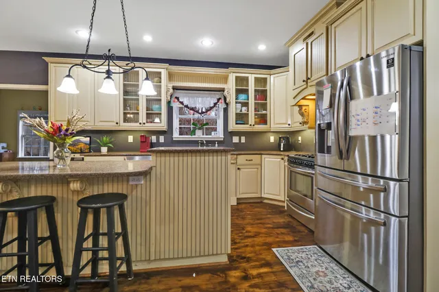 a dining room with wooden floor a chandelier a wooden table and chairs