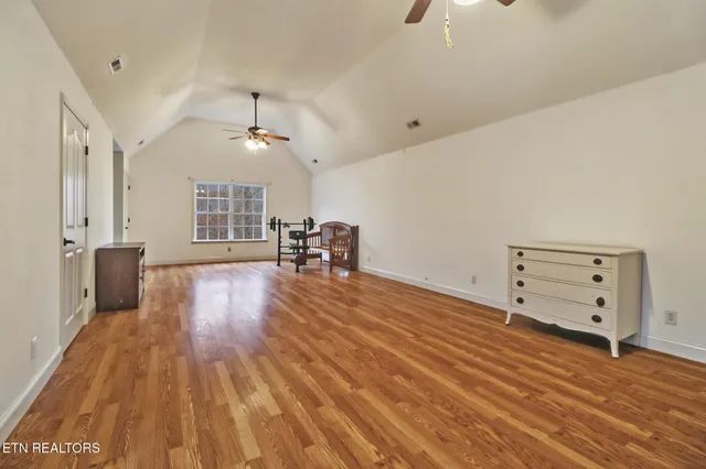 a view of empty room with wooden floor and ceiling fan