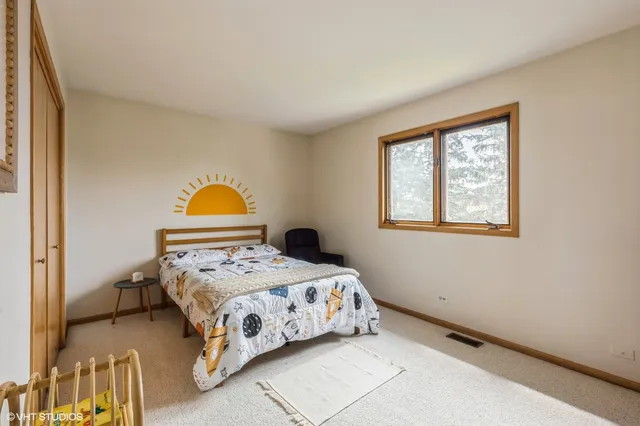 a bedroom with a bed a painting on the wall and a window