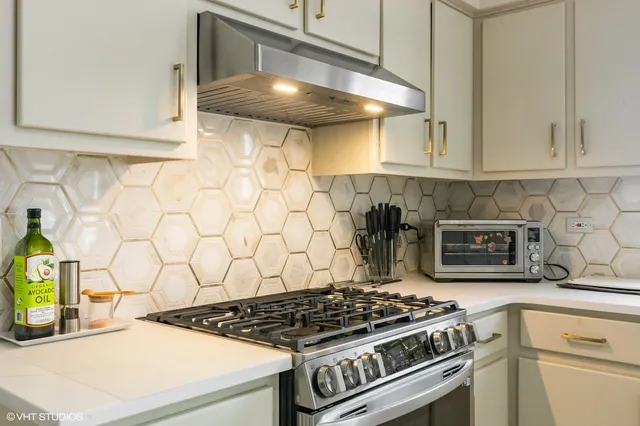 a kitchen with granite countertop a stove and a white cabinets