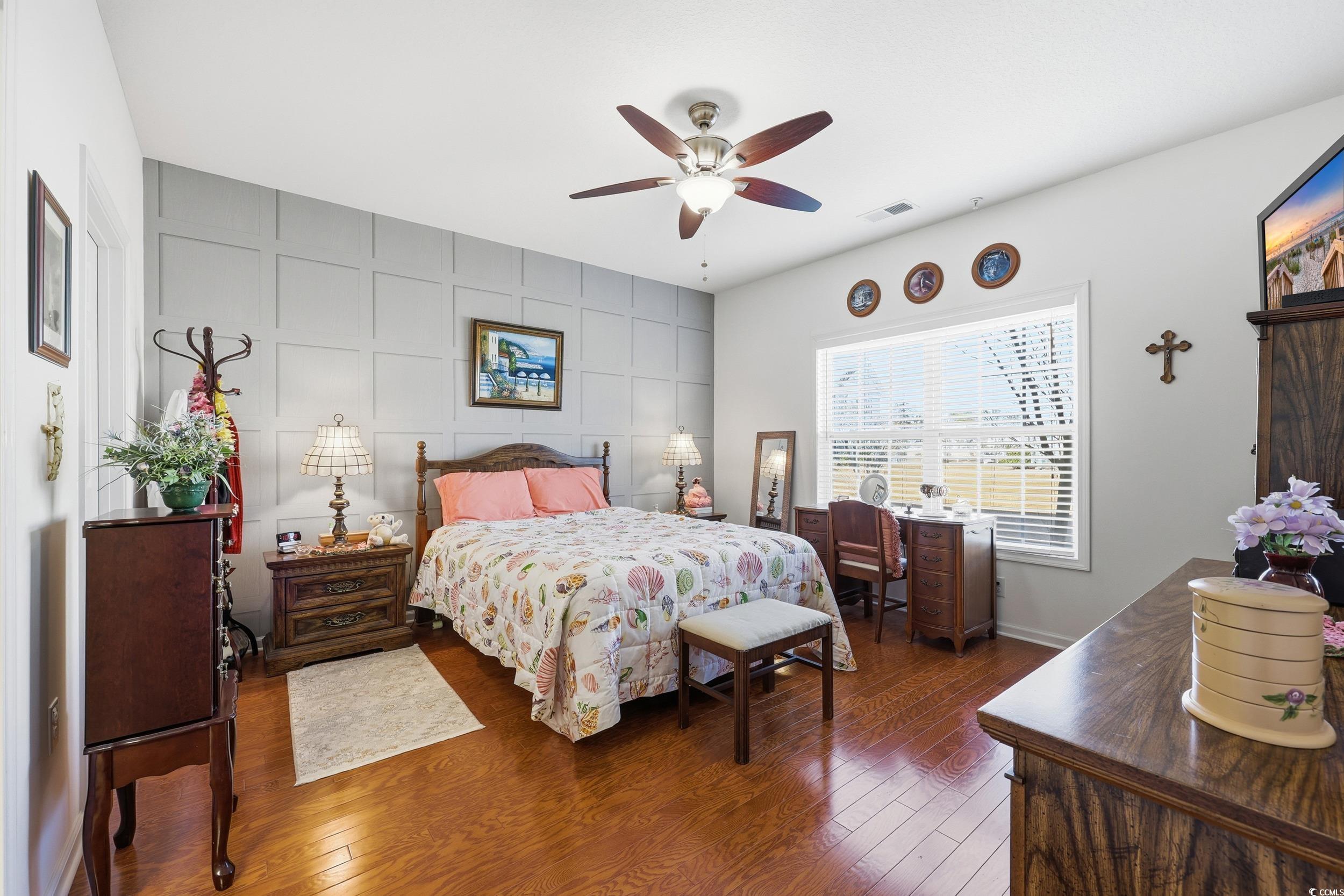 822 Sail Lane, Unit 103 Murrells Inlet, SC 29576 - Photo 20 of 37 Bedroom featuring dark wood-type flooring, a ceiling fan, and an accent wall