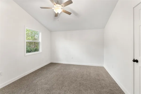 an empty room with a window and a fan