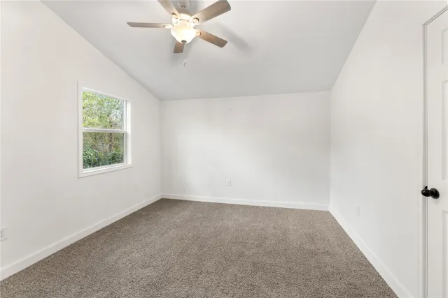 an empty room with a window and a fan