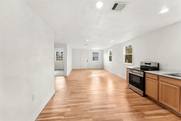 a large kitchen with stainless steel appliances granite countertop a stove and a wooden floors