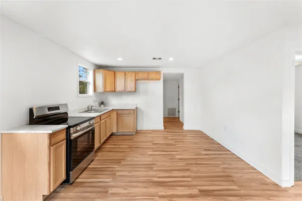 a large kitchen with stainless steel appliances a large counter top a stove a chimney a sink and a refrigerator