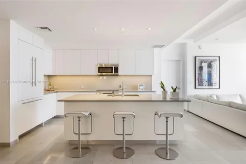 a kitchen with stainless steel appliances a sink a stove a refrigerator cabinets and chairs
