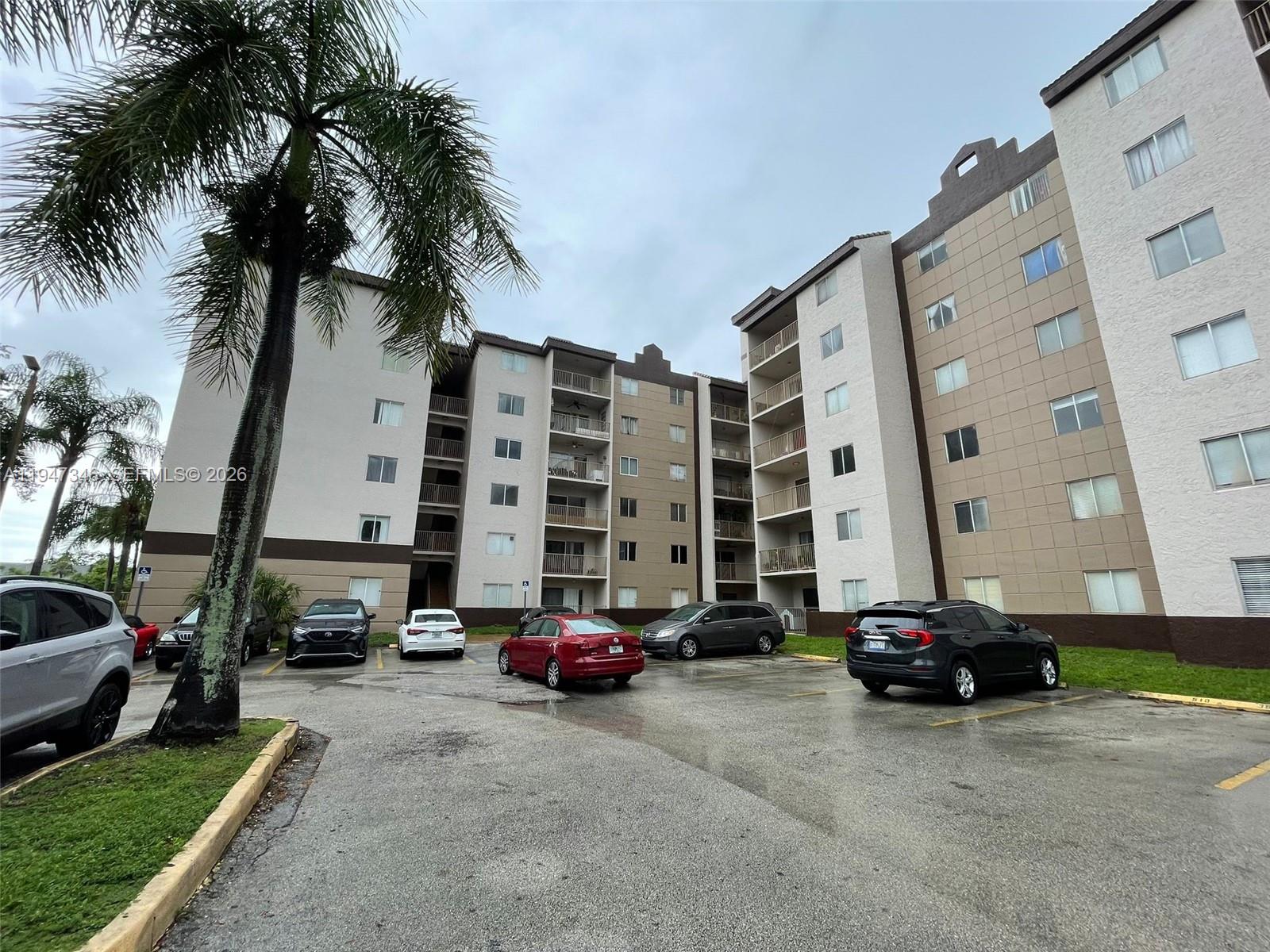 15221 Southwest 80th Street, Unit 313 Miami, FL 33193 - Photo 2 of 14 a view of a cars park in front of a building