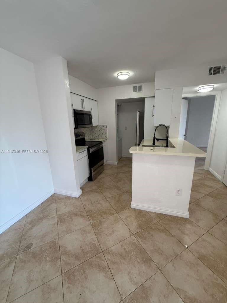 15221 Southwest 80th Street, Unit 313 Miami, FL 33193 - Photo 6 of 19 a kitchen with a sink a stove top oven and cabinets