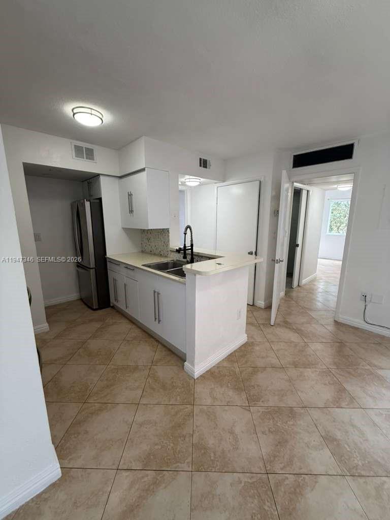 15221 Southwest 80th Street, Unit 313 Miami, FL 33193 - Photo 9 of 19 a kitchen with a sink a refrigerator and cabinets