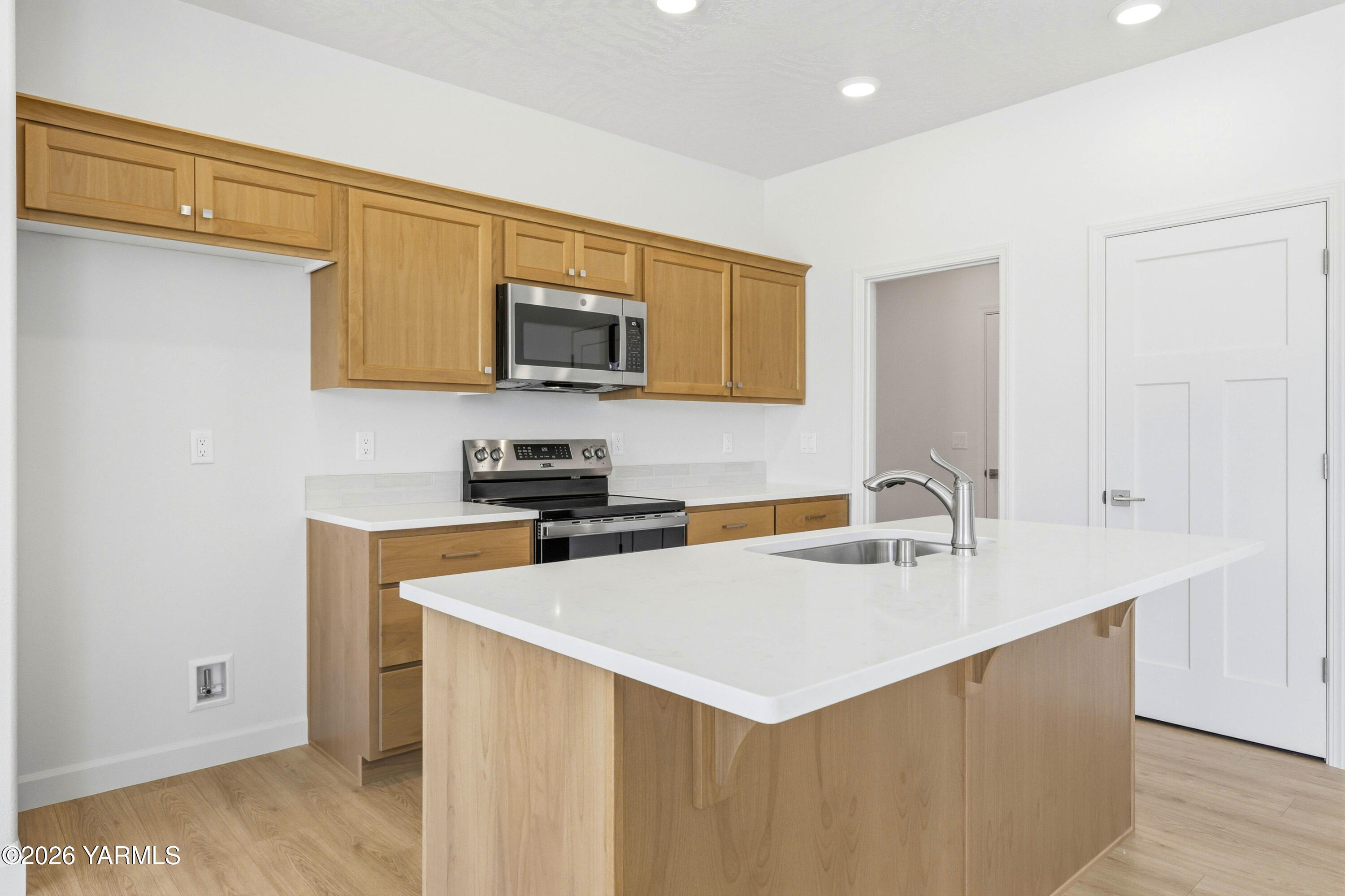 218 Packer Street Prosser, WA 99350 - Photo 11 of 36 a kitchen with stainless steel appliances a sink a stove a microwave a sink a refrigerator with white cabinets and a wooden floor