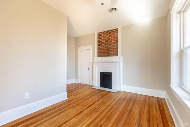 a view of empty room with wooden floor and fireplace