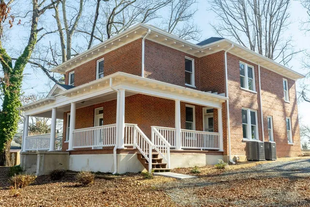 a front view of a house with a yard and large tree