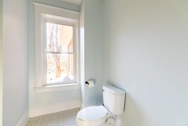 a white toilet sitting next to a window in a bathroom