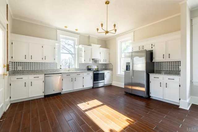 a large kitchen with stainless steel appliances sink refrigerator and white cabinets