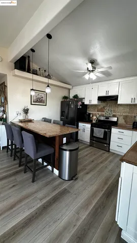 a kitchen with a stove a refrigerator and chairs
