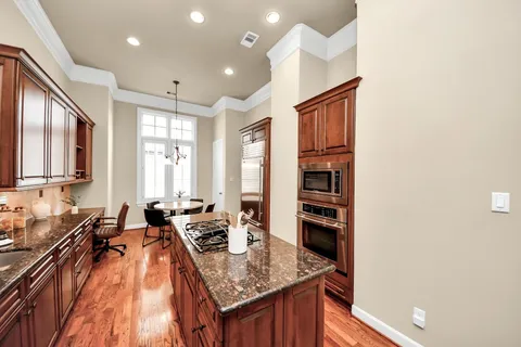 a kitchen with stainless steel appliances granite countertop a refrigerator a sink dishwasher a stove and white countertops with wooden floor