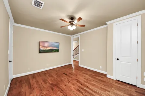 an empty room with wooden floor and a ceiling fan