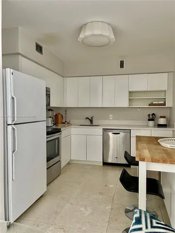 a kitchen with a refrigerator a stove and white cabinets