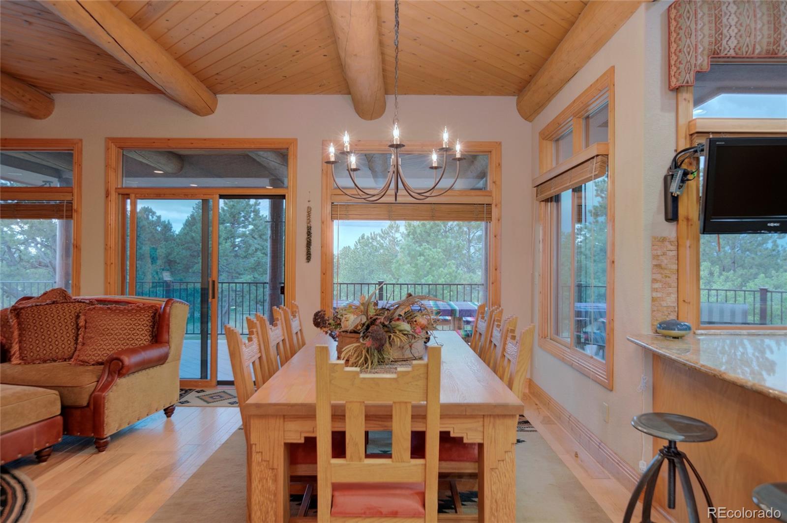11503 East Smith Road Elbert, CO 80106 - Photo 15 of 44 a view of a dining room with furniture a chandelier and large windows