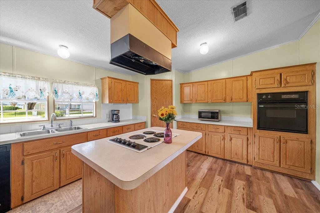 10865 Southeast Timucuan Road Summerfield, FL 34491 - Photo 16 of 35 a kitchen with a stove a sink dishwasher and white cabinets with wooden floor