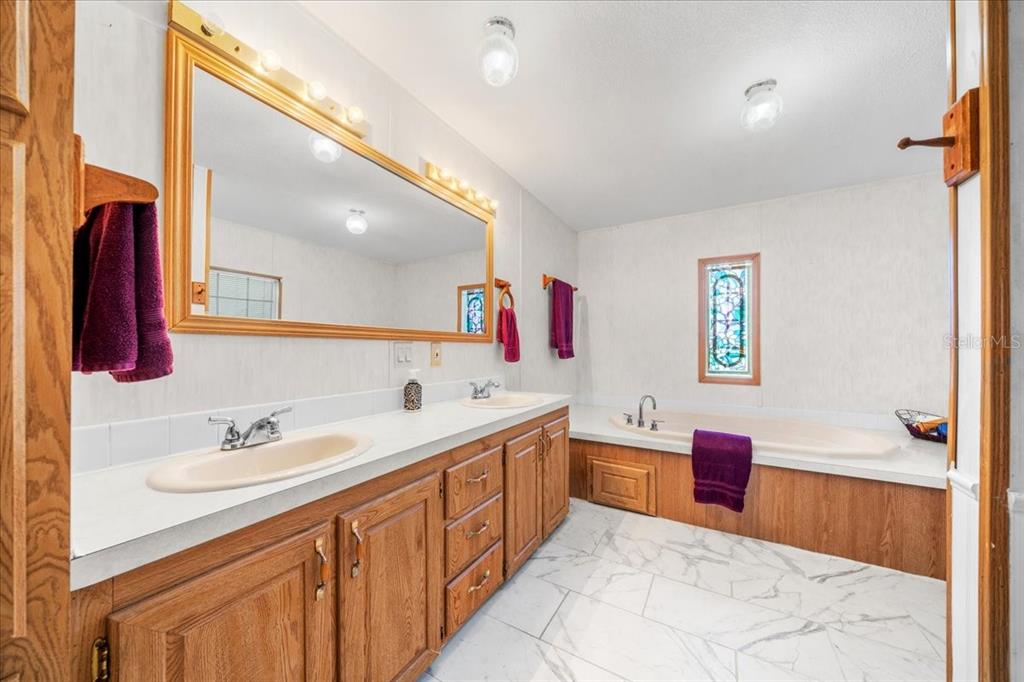 10865 Southeast Timucuan Road Summerfield, FL 34491 - Photo 21 of 35 a spacious bathroom with a tub sink and mirror