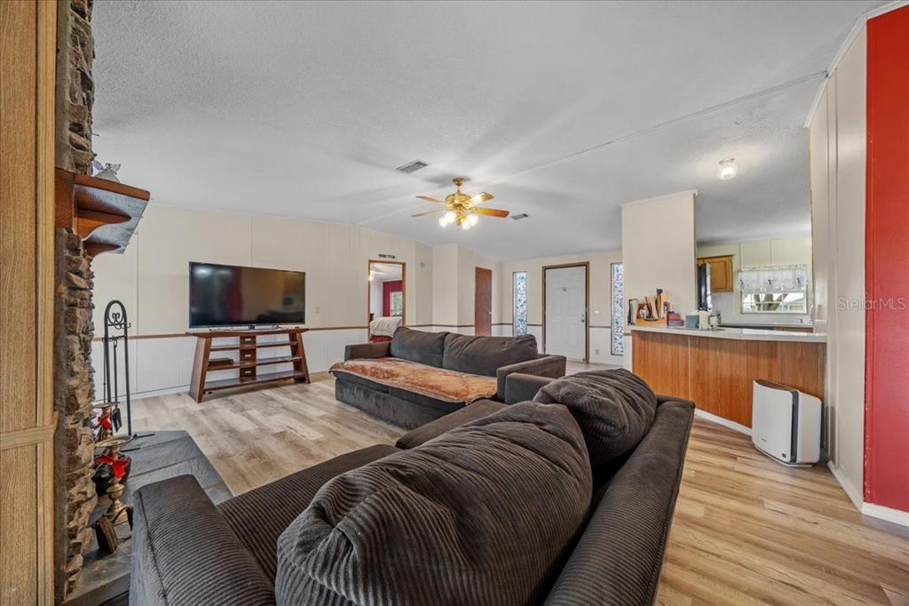 10865 Southeast Timucuan Road Summerfield, FL 34491 - Photo 8 of 35 a living room with furniture a flat screen tv and kitchen view