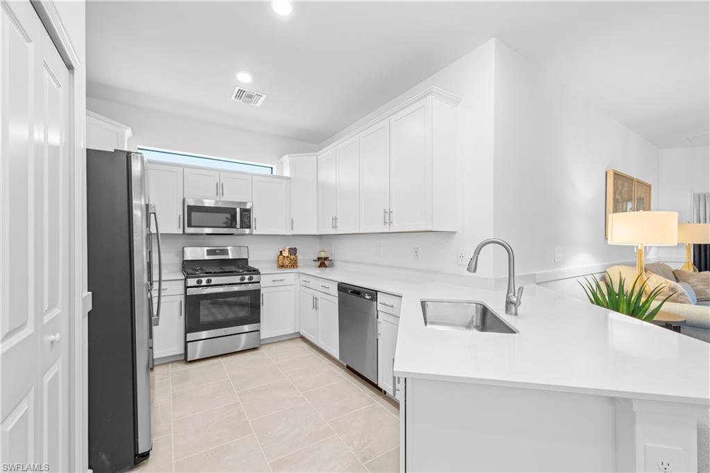 14656 Ballast Way Alva, FL 33920 - Photo 10 of 30 a kitchen with stainless steel appliances a sink a stove a refrigerator cabinets and a window