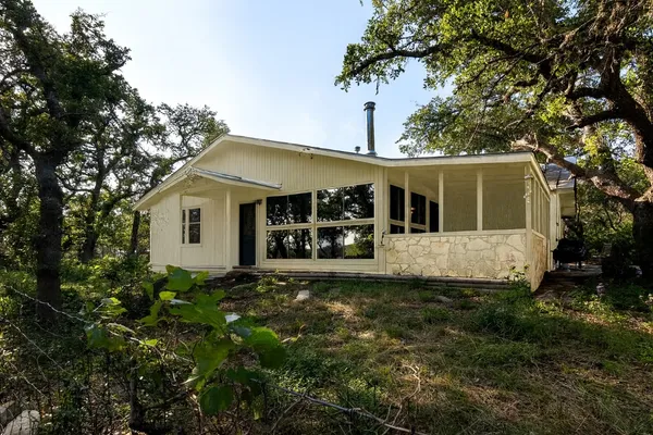 a view of a house with floor to ceiling window and a large tree
