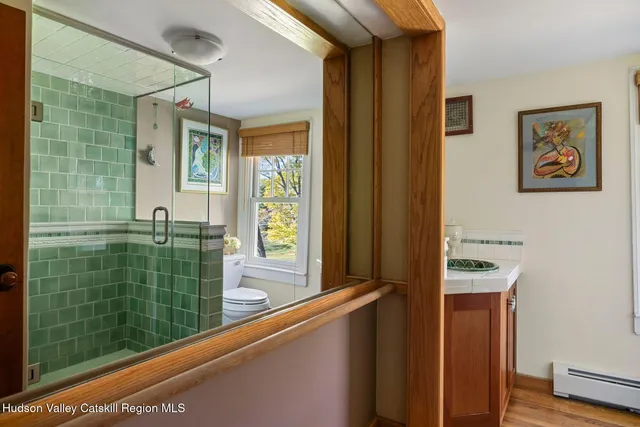 a bathroom with a granite countertop sink mirror toilet and next to a window